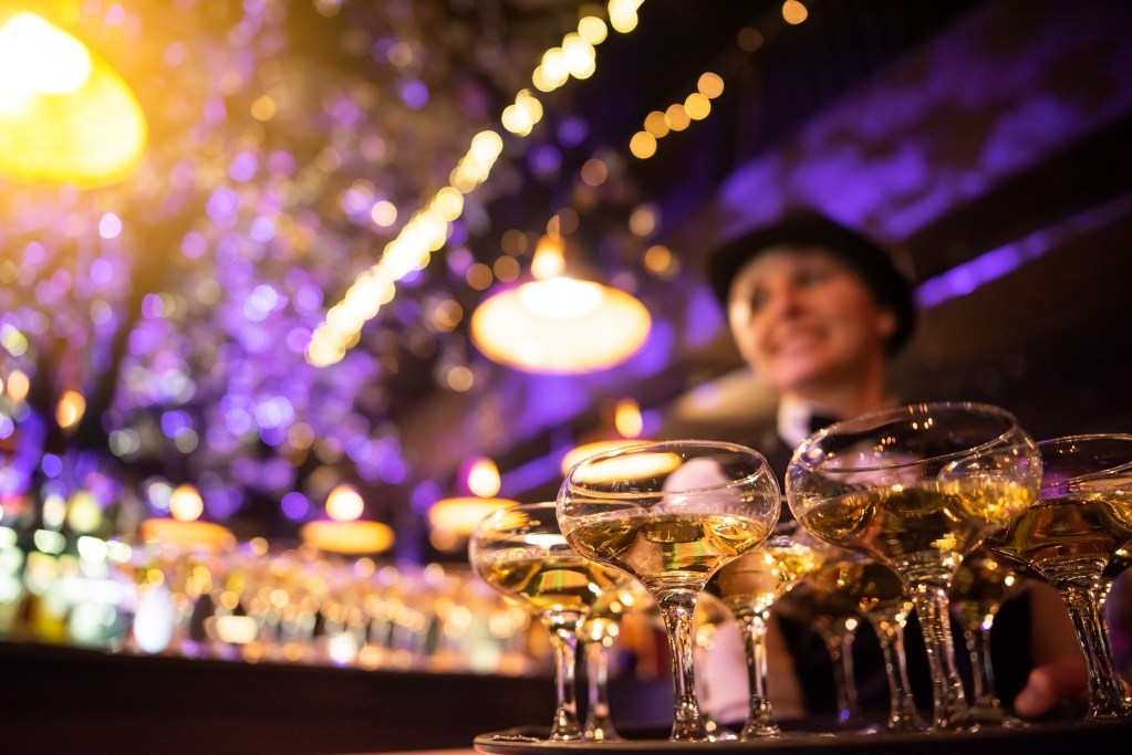 happy waitress holding a tray full of glasses or welcome drinks at an event